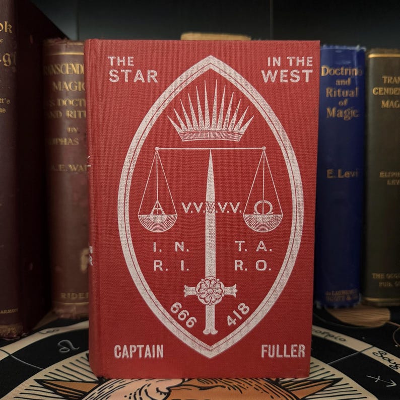 Pu&ograve; includere: Un libro rosso con un simbolo bianco sulla copertina. Il simbolo &egrave; uno scudo con una spada, una bilancia e una corona. Il titolo del libro &egrave; "The Star in the West".