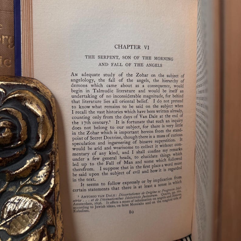 May include: A book page with text from Chapter VI, titled "The Serpent, Son of the Morning and Fall of the Angels." The text discusses angelology and related subjects. The book has a decorative gold edge.