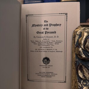 May include: A vintage book cover with the title "The Mystery and Prophecy of the Great Pyramid" by Charles S. Knight, D.D. The book is part of the Rosicrucian Library, Volume XIV. The book was published by the Rosicrucian Press in San Jose, California.