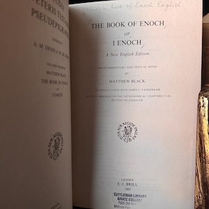 May include: Open book titled "The Book of Enoch, or 1 Enoch" by Matthew Black. The book is a new English edition with commentary and textual notes. The cover is off-white with black text. The book was published in Leiden in 1985.