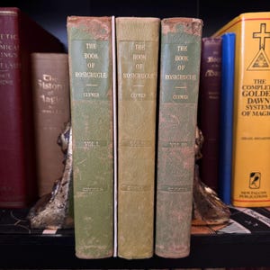 Może przedstawiać: Trzy zielone książki w twardej oprawie zatytułowane "The Book of Rosicrucie" autorstwa Clymera. Książki to tomy I, II i III.