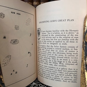 May include: A page from a book titled "Discerning God's Great Plan" with text discussing the Hermetic Axiom, "As it is below, so it is above." The text explains the relationship between the solar system, atoms, and galaxies.