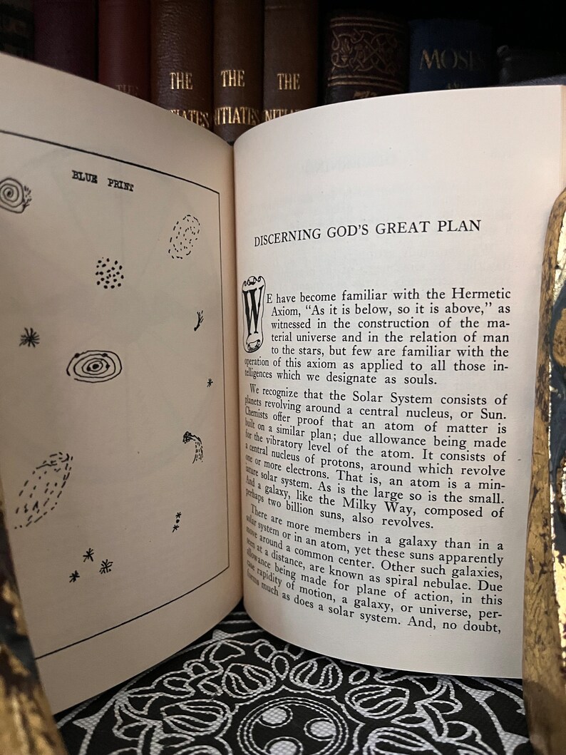 May include: A page from a book titled "Discerning God's Great Plan" with text discussing the Hermetic Axiom, "As it is below, so it is above." The text explains the relationship between the solar system, atoms, and galaxies.