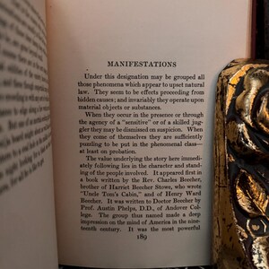 May include: A page from a book titled "Manifestations" discussing the impact of the book "Uncle Tom's Cabin" on American culture in the 19th century. The text describes the book's author, Harriet Beecher Stowe, and her brother, Charles Beecher, who wrote a book about the "sensitive" nature of the book's themes.