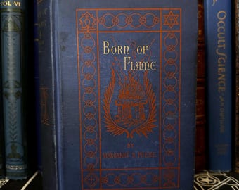 Peut inclure: Un livre relié de couleur bleue intitulé "Born of Flame" par Margaret B. Peeke. La couverture présente une illustration rouge et or d'un autel enflammé avec une étoile de David au-dessus.