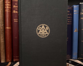 May include: A black hardcover book with a gold emblem on the front cover. The emblem is a triangle with a skull and crossbones inside. The text "TRY" is below the triangle.
