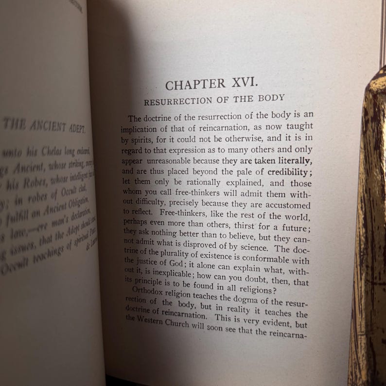 May include: Open book with text on aged paper. The text reads "CHAPTER XVI. RESURRECTION OF THE BODY" and discusses reincarnation. The book is open to a page with printed text, with the title and chapter number visible.