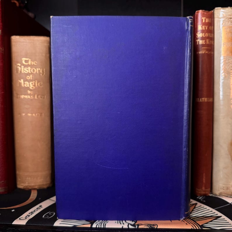 Puede incluir: Un libro de tapa dura azul con el t&iacute;tulo "The History of Magic" de "Lophpas Levi" y "E. Waite" en el lomo.