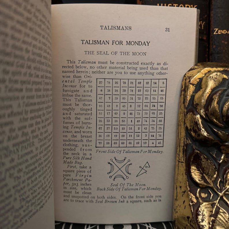 May include: A black and white illustration of a talisman for Monday, the seal of the moon. The talisman is a square with a crescent moon and a cross inside. The text "Seal of the Moon" is below the talisman. The text "Front Side of Talisman for Monday" is below the illustration. A table of numbers is shown above the illustration.