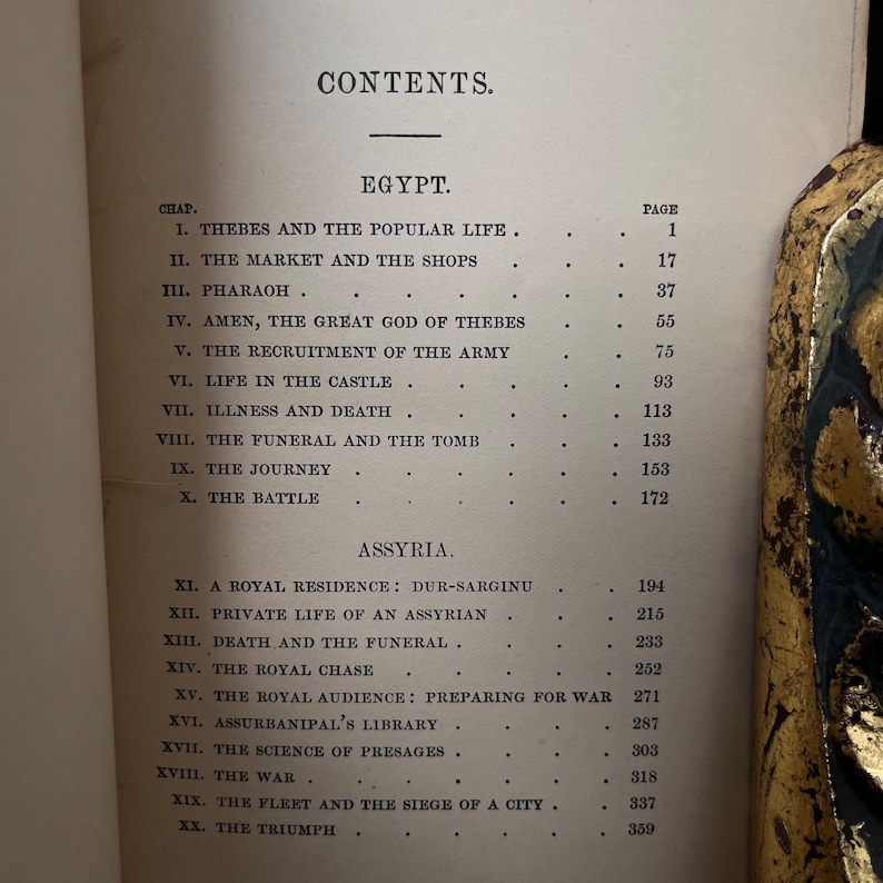 以下が含まれることがあります： 表紙に「CONTENTS」と印刷された白黒の本。この本は、古代エジプトとアッシリアに関する物語の章とページ番号をリストしています。