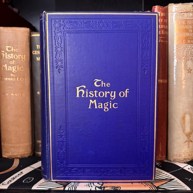 Puede incluir: Un libro de tapa dura azul con letras doradas en el lomo y la portada. El t&iacute;tulo del libro es "The History of Magic".