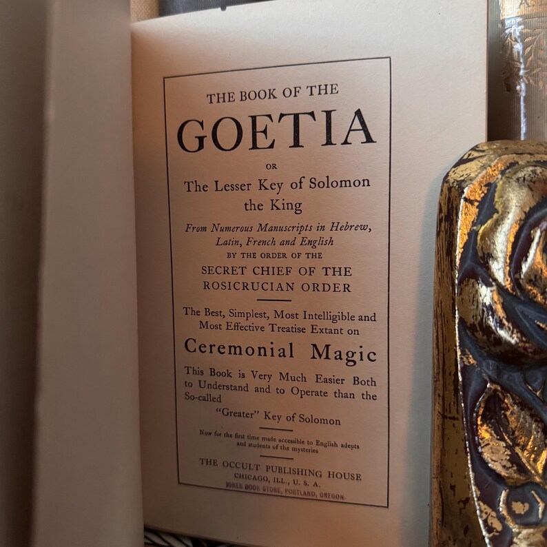 Op de afbeelding: Open boek met de titel "The Book of the Goetia" en de ondertitel "The Lesser Key of Solomon the King". De tekst beschrijft de inhoud van het boek over ceremoni&euml;le magie, afkomstig van Hebreeuwse, Latijnse, Franse en Engelse manuscripten.