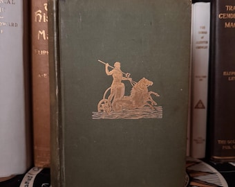 May include: A vintage hardcover book with a dark green cover. The cover features a gold illustration of a figure in a chariot pulled by a seahorse. Other books are visible in the background.