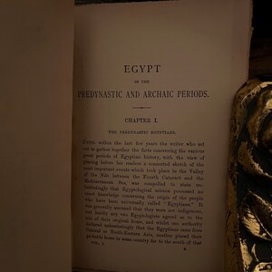 May include: A close-up of a page from a book titled "Egypt in the Predynastic and Archaic Periods." The page features a chapter titled "The Predynastic Egyptians." The text discusses the origins of the Egyptian people and the challenges of tracing their history.