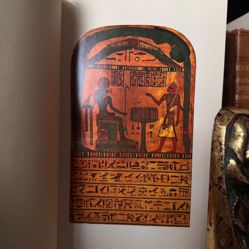 May include: An illustration of an ancient Egyptian artifact. The artwork features hieroglyphs and figures in shades of red, brown, and gold. The figures are depicted in traditional Egyptian attire, with one seated and another standing. The background is a warm, earthy tone.