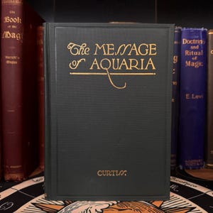 May include: A green hardcover book with gold lettering titled "The Message of Aquaria" by Curtis.