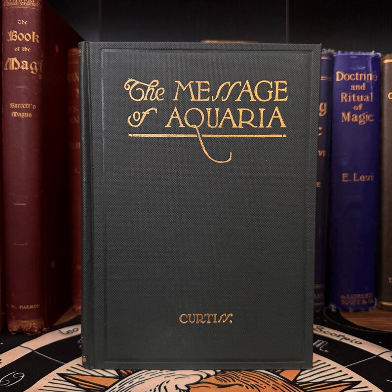 May include: A green hardcover book with gold lettering titled "The Message of Aquaria" by Curtis.