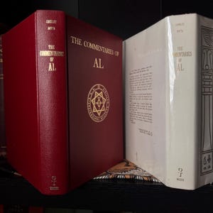 May include: Three hardcover books with the title "The Commentaries of AL" in gold lettering. The books are in red and white with gold accents. The red book has a gold emblem. The books are on a black shelf.