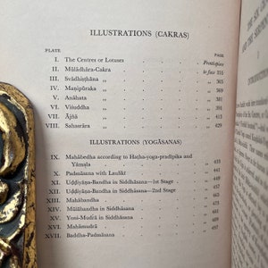 May include: A black and white book with the title "Illustrations (Cakras)" and "Illustrations (Yogasanas)" on the cover. The book lists different plates and pages for each illustration.
