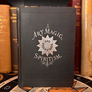 May include: A black book with silver lettering on the cover. The title is "Art Magic Spiritism." The cover also features a silver star with the words "God Understands" inside.