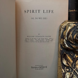 May include: A vintage book titled "Spirit Life or, Do We Die?" by William Dunseath Eaton. The book cover is white with black text and is published by Stanton and Van Vliet in Chicago.