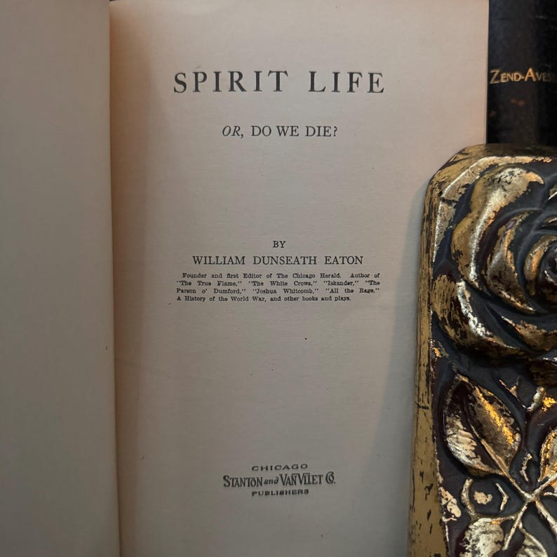May include: A vintage book titled "Spirit Life or, Do We Die?" by William Dunseath Eaton. The book cover is white with black text and is published by Stanton and Van Vliet in Chicago.