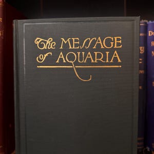 May include: A dark green hardcover book with gold lettering on the front cover. The title is "The Message of Aquaria".