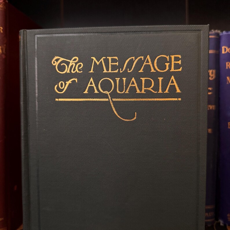 May include: A dark green hardcover book with gold lettering on the front cover. The title is "The Message of Aquaria".