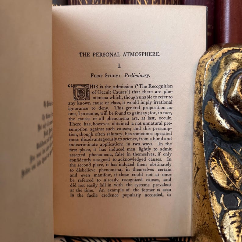 Puede incluir: Libro abierto con el t&iacute;tulo "THE PERSONAL ATMOSPHERE." La p&aacute;gina muestra texto con el encabezado "FIRST STUDY: Preliminary." El texto trata sobre el reconocimiento de causas y fen&oacute;menos ocultos.
