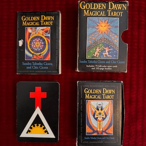 May include: A set of four tarot card decks, each with a black background and gold lettering. The decks are titled "Golden Dawn Magical Tarot" and feature illustrations of a sun, a cross and triangle, a woman with a sword, and a woman with a crown. The decks are by Sandra Tabatha Cicero and Chic Cicero.