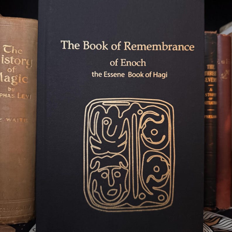 May include: A black book titled "The Book of Remembrance of Enoch" with gold lettering and an intricate gold design. The book is part of a collection of antique books, with a tan book on the left and other books on the right.