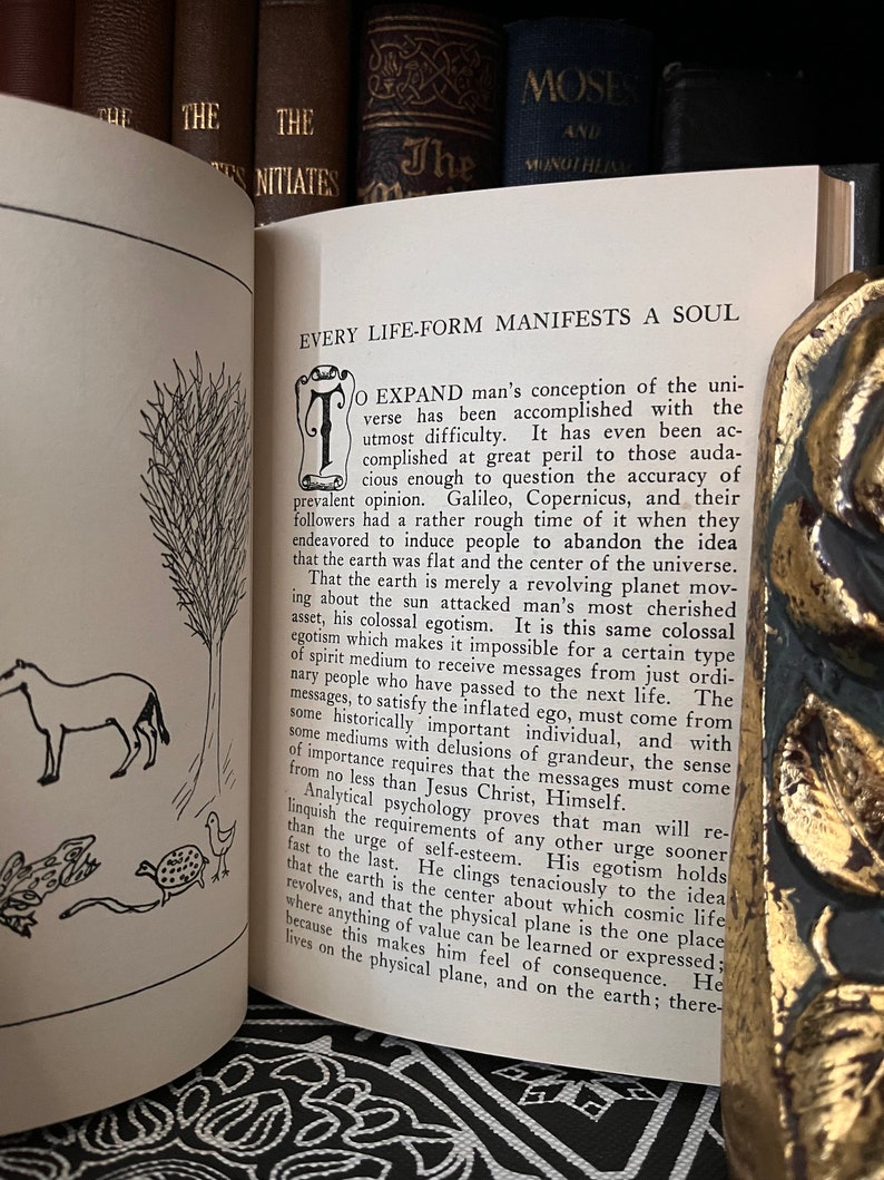 May include: A vintage book with a black and white illustration of a horse and a turtle on the cover. The book's title is "Every Life-Form Manifests a Soul".