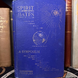 May include: A blue book titled "Spirit Mates: A Symposium" with gold lettering. The book cover features a globe, a star with an eye in the centre, and the text "The World is My Parish".