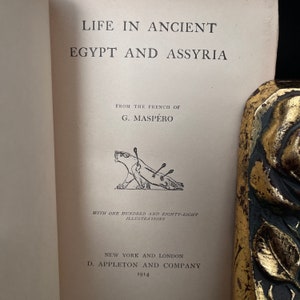 以下が含まれることがあります： G. マスペロ著「古代エジプトとアッシリアの生活」というタイトルの本の表紙。表紙には、矢が突き出ている生き物の白黒のイラストが描かれている。