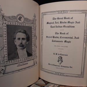 Pu&ograve; includere: Una fotografia in bianco e nero di un uomo con i baffi e in abito. La foto &egrave; incorniciata con un bordo decorativo. Il testo sulla pagina recita "The Great Book of Magical Art, Hindu Magic And East Indian Occultism" e "The Book of Secret Hindu, Ceremonial, And Talismanic Magic".