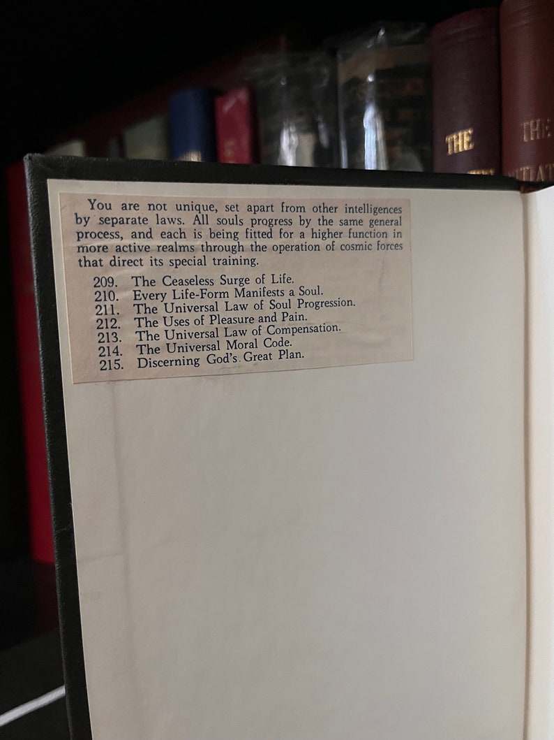 May include: A close-up of a book page with a white background and black text. The text discusses the progression of souls and the operation of cosmic forces. The page numbers are 209 through 215.