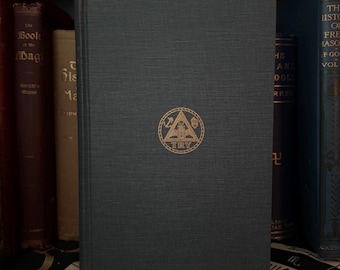 May include: A dark blue hardcover book with a gold embossed triangle symbol and the word "TRY" on the front cover. The book is on a shelf with other books.
