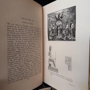 Puede incluir: Una ilustraci&oacute;n en blanco y negro de una p&aacute;gina de libro con texto sobre la magia en la India. El texto trata sobre los descendientes de Ca&iacute;n y las tradiciones originales de fratricidio. La p&aacute;gina tambi&eacute;n incluye dos ilustraciones en blanco y negro de figuras con vestimenta tradicional.