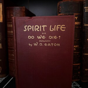 May include: A burgundy hardcover book with gold lettering on the spine and front cover. The title is "Spirit Life or Do We Die?" by W. D. Eaton.