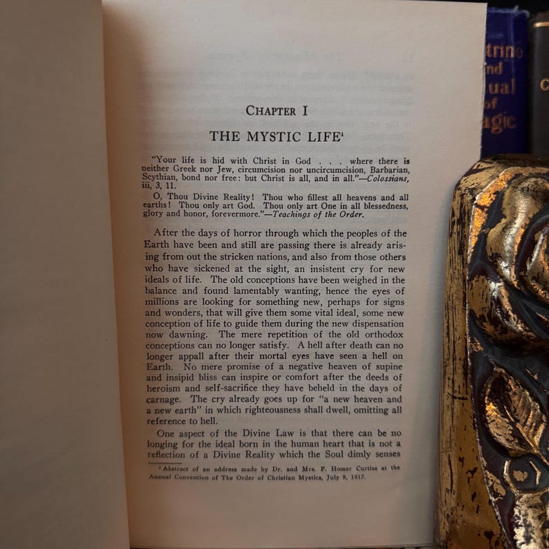 May include: A vintage book with a gold-colored bookmark. The book is open to a chapter titled "The Mystic Life" and features text about the search for new ideals and conceptions of life. The text includes quotes from the Bible and the teachings of a spiritual order.