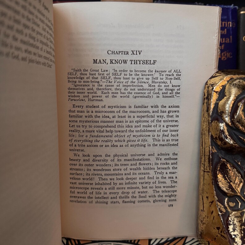 May include: A vintage book with a tan leather cover and gold lettering. The title of the book is "Man, Know Thyself" and the text on the page discusses the concept of mysticism and the universe.