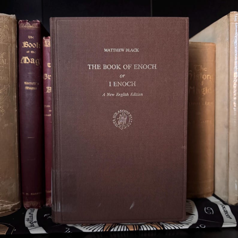 May include: A brown hardcover book titled "THE BOOK OF ENOCH or I ENOCH" by Matthew Black. The book has a textured cover and is part of a collection of antique books. The title and author are in a serif font.