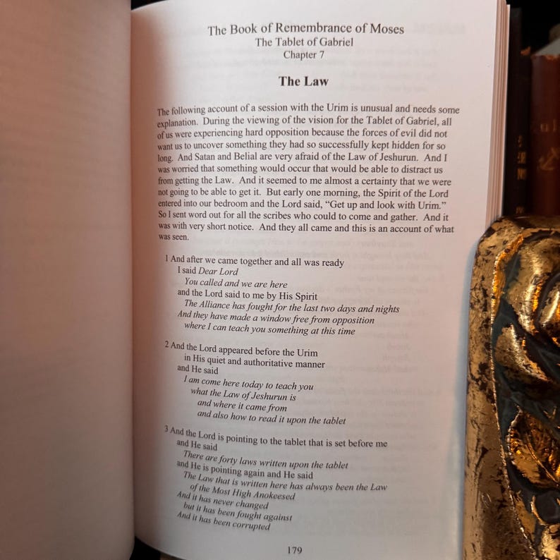 Peut inclure: Livre ouvert avec le titre "Le Livre du Souvenir de Mo&iuml;se" et "La Tablette de Gabriel". Le texte d&eacute;crit une session avec l'Urim et la Loi de Jeshurun. Le num&eacute;ro de page 179 est visible.