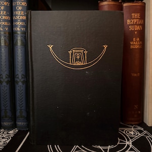 May include: A black book with gold lettering on the cover. The title is "The Egyptian Sudan" by E.A. Wallis Budge. The book is part of a set of books on a shelf.