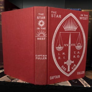 Pu&ograve; includere: Un libro rilegato in rosso intitolato "The Star in the West" di Captain Fuller. La copertina presenta una stella bianca con un sole che sorge alle sue spalle e una bilancia con una spada e una corona.