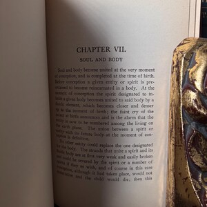 May include: Open book with text titled "CHAPTER VII. SOUL AND BODY." The text describes the union of soul and body at conception and the process of reincarnation. A decorative, ornate object is partially visible on the right side.