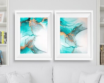 Puede incluir: Dos impresiones de arte abstracto enmarcadas con pintura turquesa y dorada. Las impresiones están colgadas en una pared blanca sobre un sofá blanco con almohadas blancas.