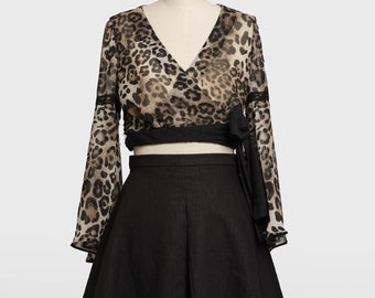 May include: A black skirt with a leopard print top. The top has long sleeves and a tie at the waist.