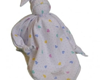 May include: A white muslin baby comfort toy with a knotted head and a hat. The toy is decorated with small multi-colored hearts and the text "Sweet Dreams".