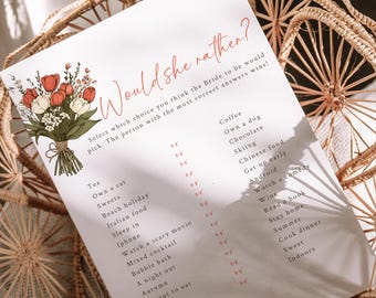 May include: A white card with the text "Would she rather?" in pink script. The card has a floral illustration in the top left corner and a list of 20 questions with check boxes next to each question. The questions are about the bride's preferences.